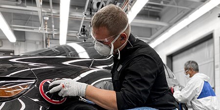 Kuvassa mies käyttää premium-hiomatuotteita ja premium-työkaluja autossa saavuttaakseen erinomaisia tuloksia.
