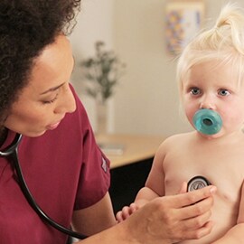 Lastensairaanhoitaja, joka kuuntelee pikkulapsen rintaa 3M Littmann Classic III -stetoskoopilla. 