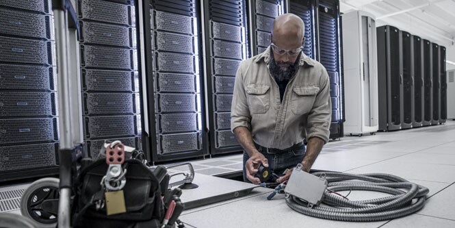 medarbetare på datacenter som installerar en kabelränna under golvet
